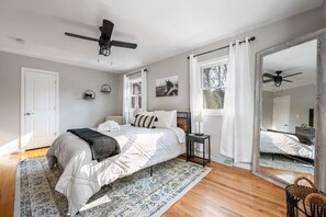 Een slaapkamer met een bed, nachtkastje en plafondventilator.