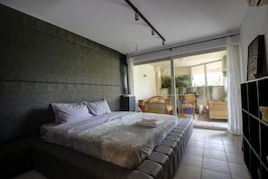A modern bedroom with a large bed, a sofa, and a sliding glass door leading to a balcony. - 3 Bedroom Apartment Elias Total (Platanias)