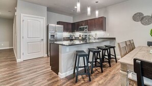 Een moderne keuken met donker houten kastjes, roestvrijstalen apparatuur en een centraal kookeiland met barstoelen.