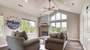 Ein geräumiges Wohnzimmer mit Kamin, zwei Sofas und Deckenventilator.