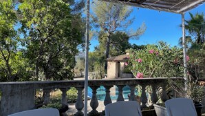 A covered outdoor area with a stone balustrade, a small building, and lush greenery. - Villa Grand Cédre - Family house with infinity pool, garden 4000m2. (Marseille)