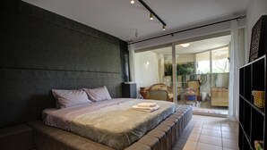 A modern bedroom with a large bed, a dark accent wall, and a sliding glass door leading to a balcony. - 2 Bedroom Apartment on Beach Elias Lower (Platanias)