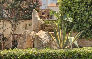 A garden with rocks, a chair, and a large aloe plant.