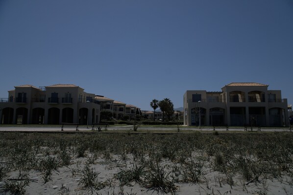 A coastal building with multiple balconies and a sandy foreground.