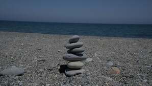A stack of smooth, rounded stones on a pebble beach with a calm sea in the background. - 1 Bedroom Apartment on Beach Elias Upper (Platanias)