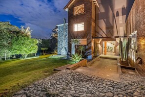 A modern house with a stone facade, a well-maintained lawn, and a variety of plants. - Espigal 2 · Mansión de lujo Alto Palmas-5Hab Piscina y Jacuzzi (Envigado)