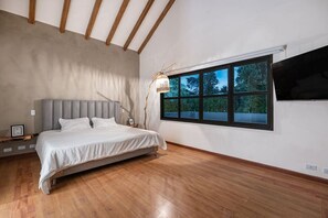 A bedroom with a bed, a window, and a TV on the wall. - Espigal 2 · Mansión de lujo Alto Palmas-5Hab Piscina y Jacuzzi (Envigado)