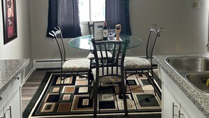 Una cocina moderna con comedor, ventilador de techo, reloj y ventana con cortinas.
