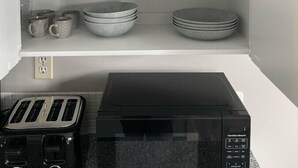 Una cocina con armarios blancos, un tostador negro y un microondas.
