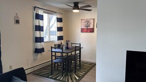 Un espace repas comprenant une table, des chaises, un ventilateur de plafond et un tableau accroché au mur.