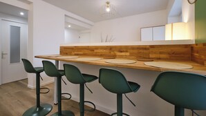 A modern kitchen with a wooden countertop, four bar stools, and a pendant light.