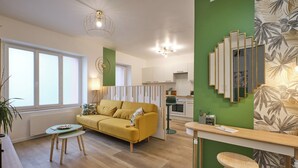 A modern living room with a yellow sofa, a small table, and a green accent wall.