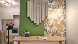 A modern kitchen with white cabinets, a green accent wall, and a wooden dining table with a notebook and pens.