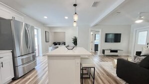 A modern kitchen with a central island, stainless steel appliances, and a dining area with a black sofa.