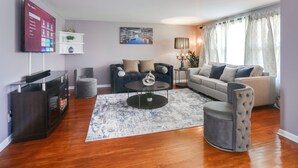 Een moderne woonkamer met een flatscreen televisie, een bank, een tweezitterbank, een salontafel en een open haard.