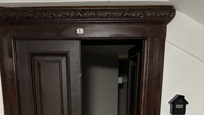 Una puerta de madera oscura con un tirador de latón y una placa de latón pequeña encima.
