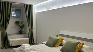 Una habitación de hotel moderna con cama, mesita de noche, espejo y ventana con cortinas.