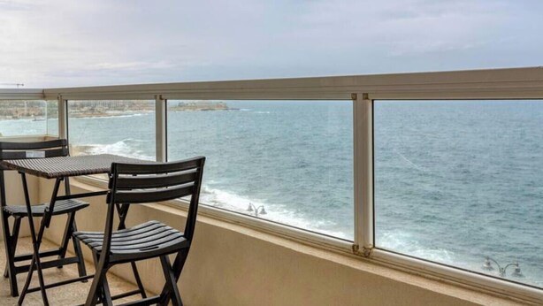 A balcony with a view of the sea, two chairs, and a table. - Tower Road seafront home, with 3BR & Working Space (Sliema)