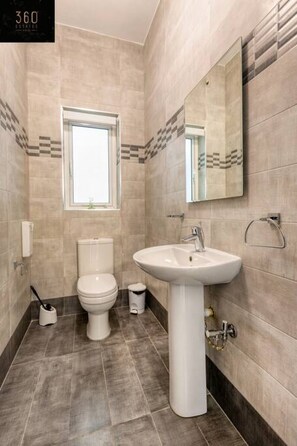 Ein modernes Badezimmer mit Toilette, Waschbecken und Fenster.