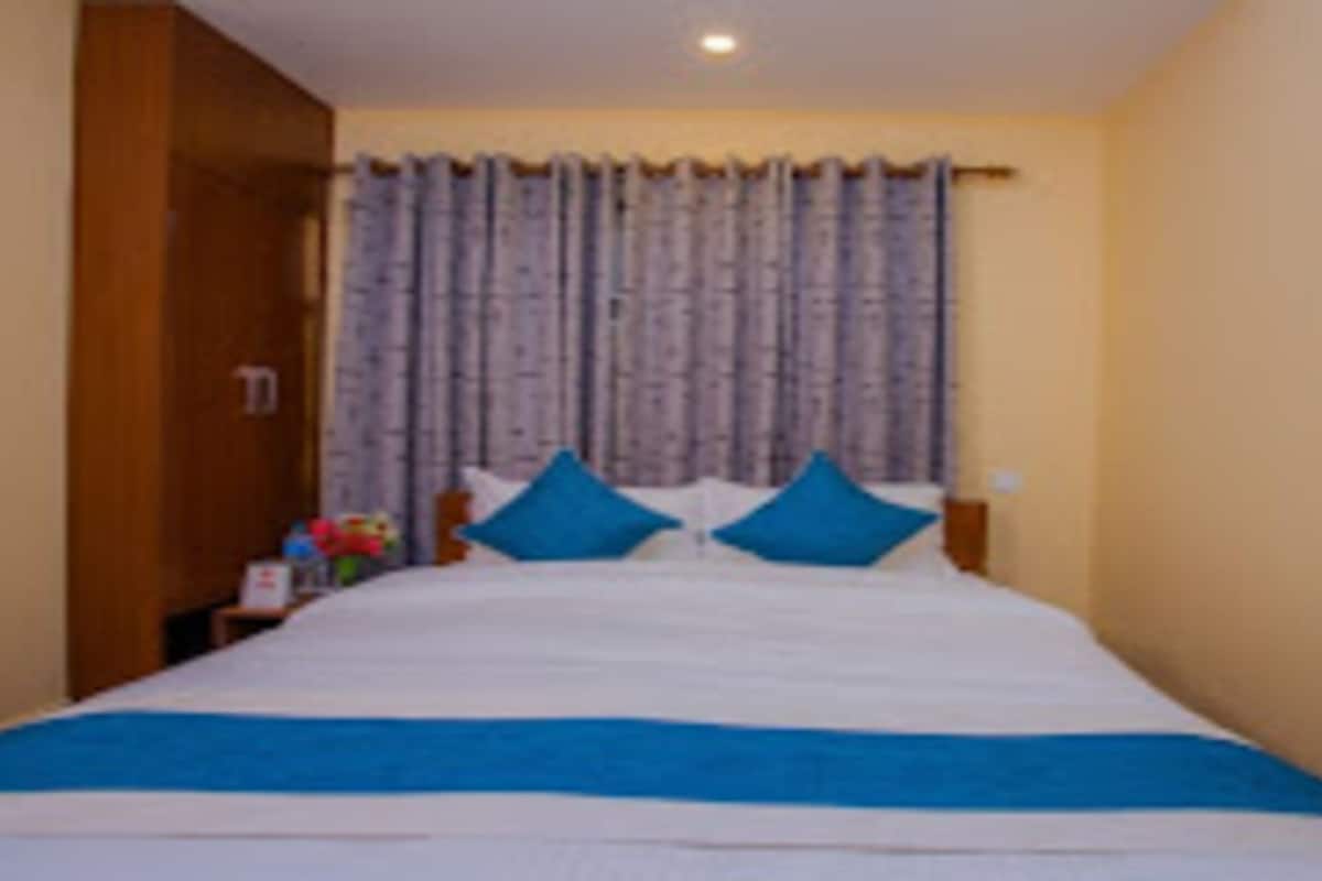 Un dormitorio con una cama, almohadas azules y una cortina.