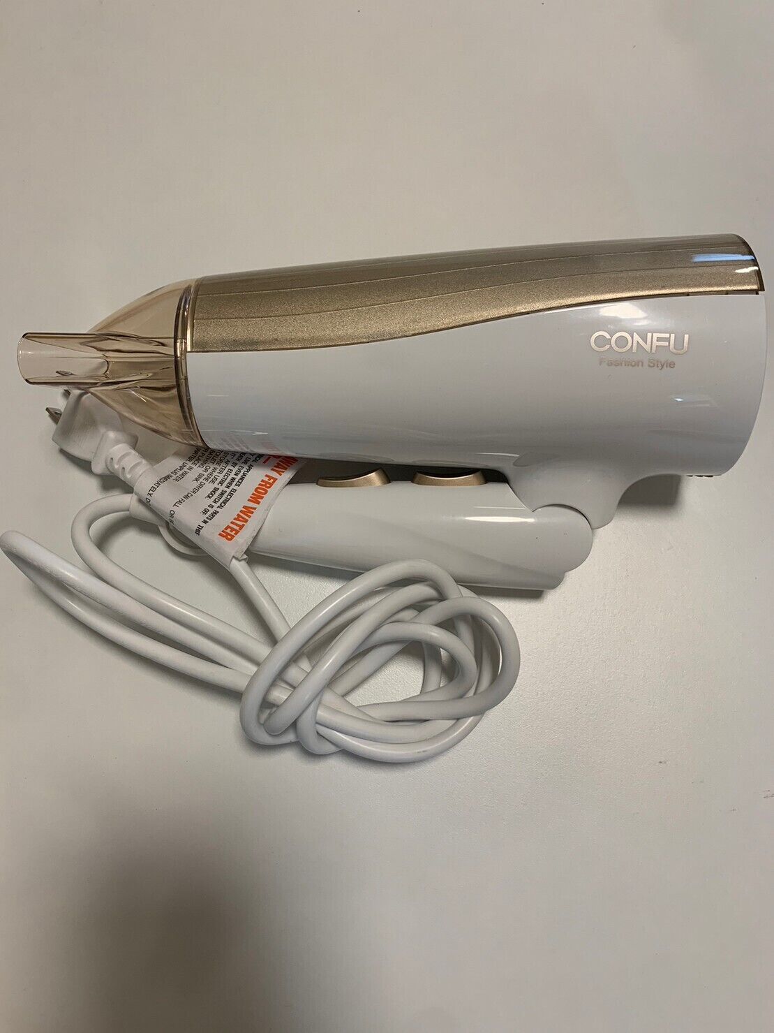 Ein weißer Haartrockner mit goldener Verzierung und einem weißen Stromkabel.