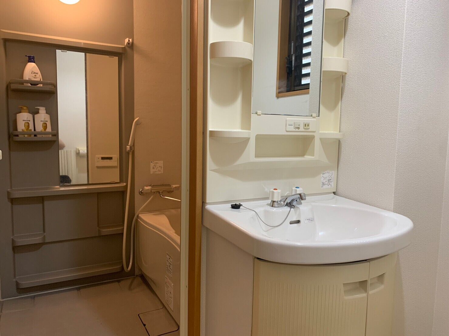A bathroom with a white sink, mirror, and shelves with toiletries.