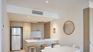 Una cocina moderna con una isla central, taburetes de bar y una mesa de comedor con sillas.