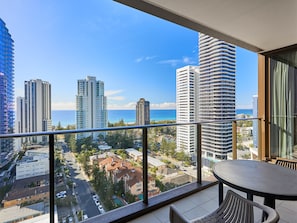 Enjoy a coastal city view from this balcony with a round table and two chairs.