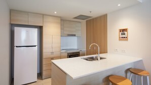 Una cocina moderna con isla integrada, pileta de acero inoxidable y taburetes de madera.