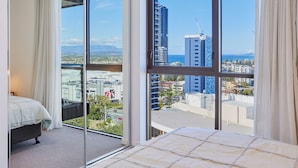 Un dormitorio con una ventana grande que ofrece vistas a la ciudad y al mar.