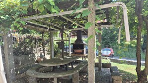 A rustic outdoor area with a stone bench, a metal grill structure, and a pergola with climbing plants. - Executive Huge Flat in Central Lugano (Lugano)