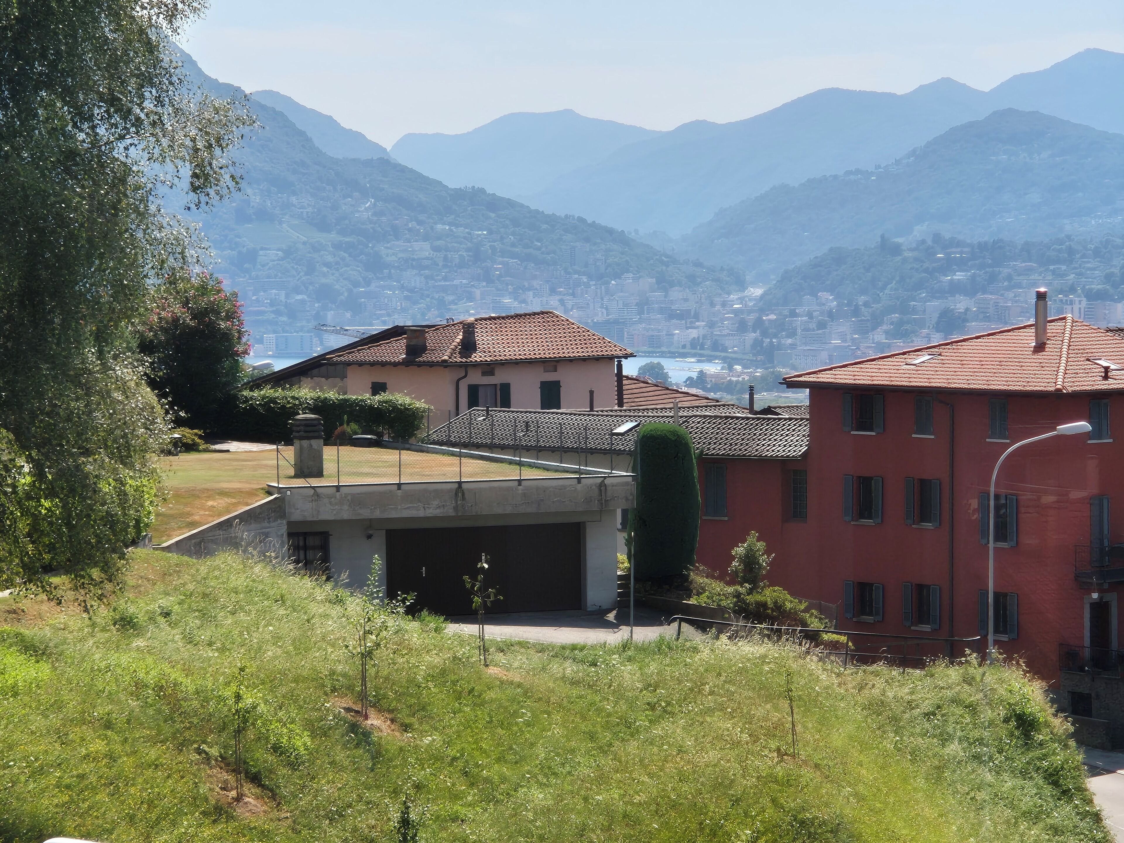 A residential area with houses, a clear view of the mountains, and a body of water in the distance.
