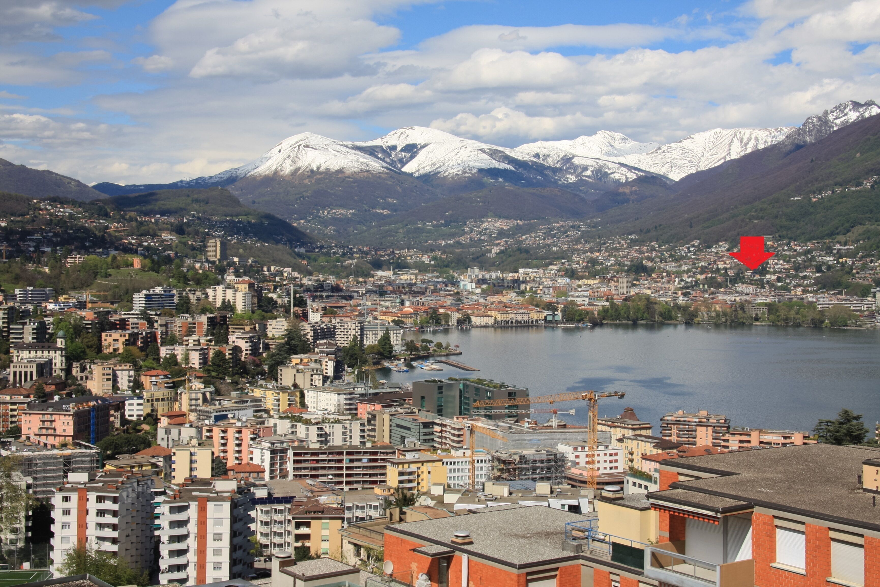 A cityscape with a lake, mountains, and a red arrow pointing to a specific location.