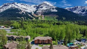 Een lodge met meerdere gebouwen, omringd door dicht bos en besneeuwde bergen.