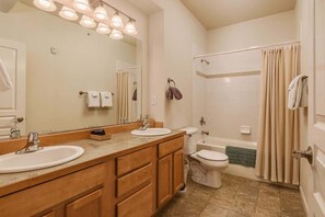Ein Badezimmer mit zwei Waschbecken, einer Toilette, einer Badewanne und einer Duschvorhang.