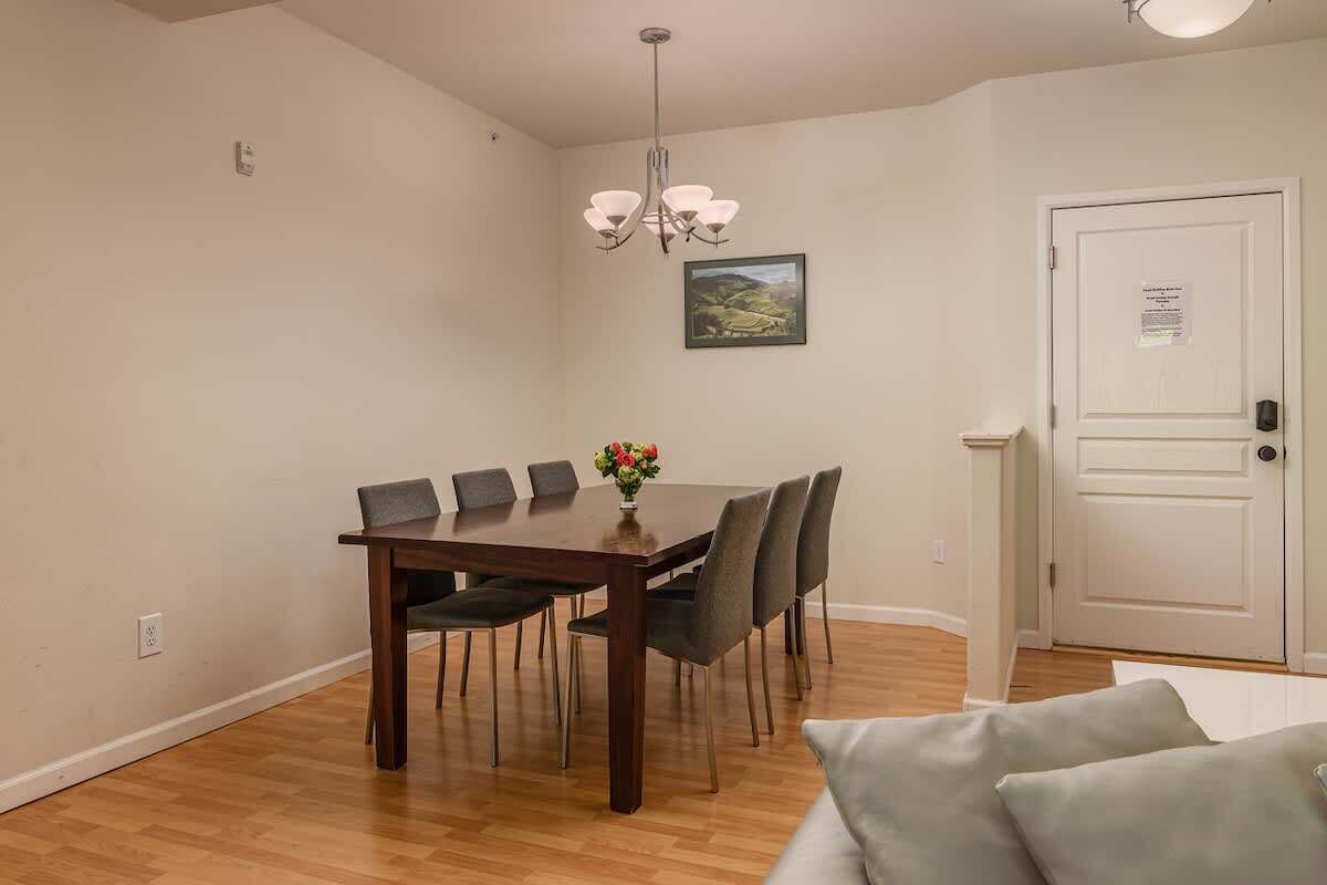 A dining area with a wooden table and chairs, a chandelier, and a door with a sign.