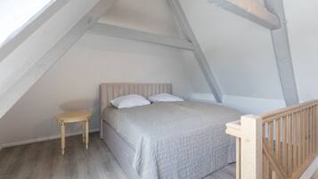 A bedroom with a bed, a small table, and a wooden railing.