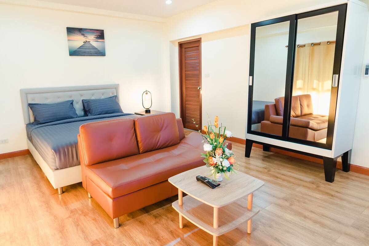 A bedroom with a bed, a sofa, a coffee table, and a wardrobe.