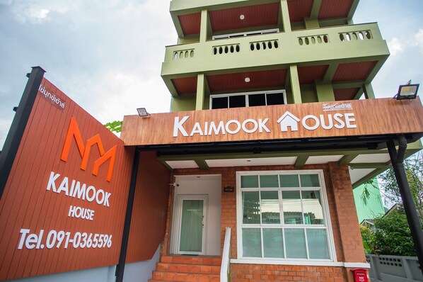 A building with a sign reading "Kaimook House" and a contact number.