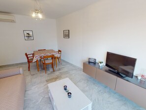 A living room with a dining table, chairs, a sofa, a TV, and a coffee table. - Spacious 2-Room Apartment with A/C, Terrace & Garage Near Menton Center (Menton)