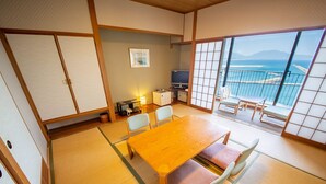 A traditional Japanese room with tatami flooring, a wooden table, and a view of the sea. - Kokumin Shukusya Marin Terrace Ashiya (Ashiya)