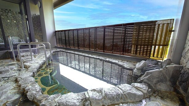 A stone hot tub with a wooden fence and a clear view of the sky. - Kokumin Shukusya Marin Terrace Ashiya (Ashiya)