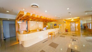 A hotel reception area with a wooden reception desk, a clock, and a small table. - Kokumin Shukusya Marin Terrace Ashiya (Ashiya)