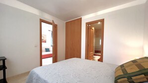 A bedroom with a bed, wooden wardrobe, and a door leading to a bathroom.