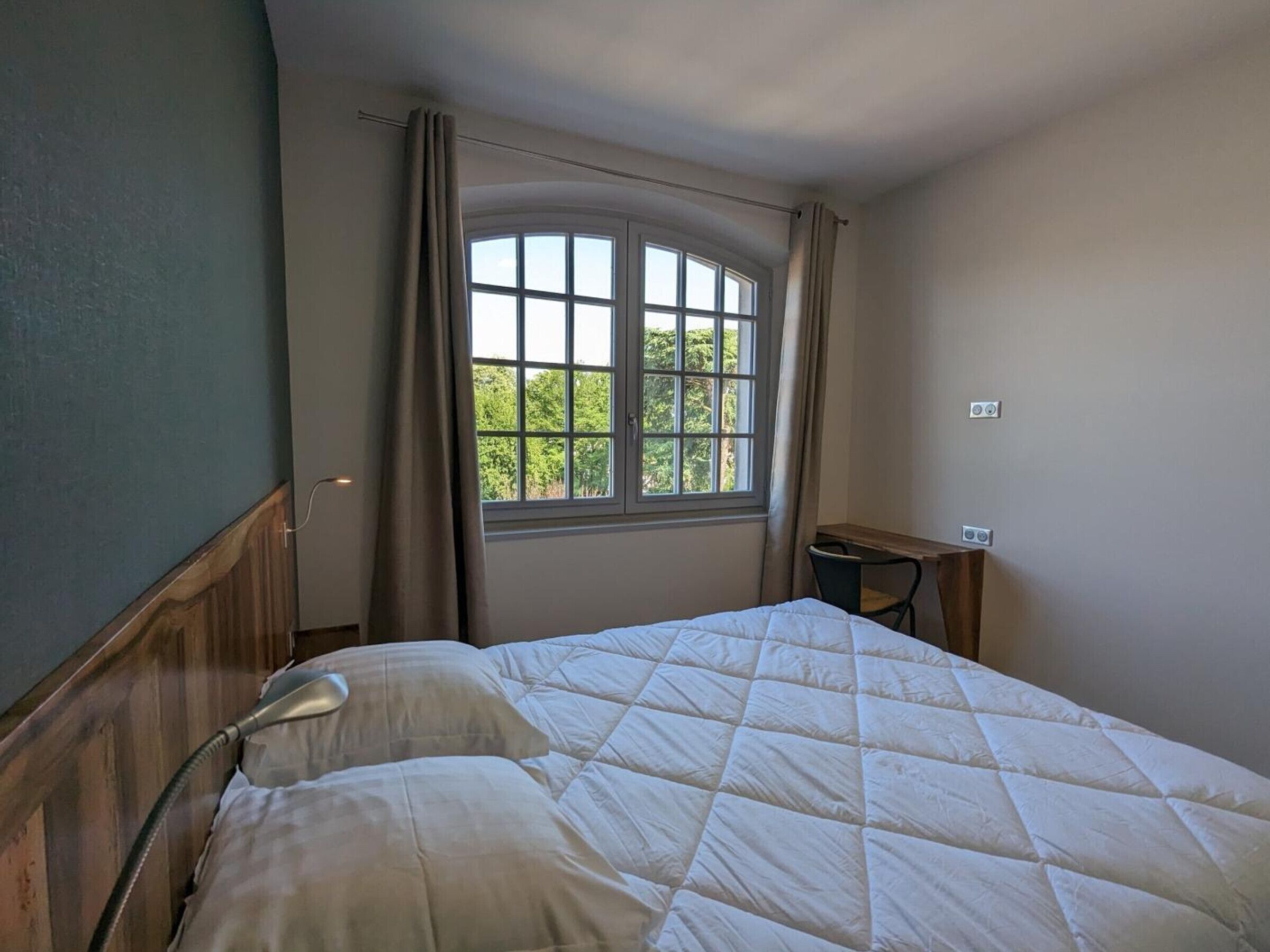 Un dormitorio con cama, ventana y escritorio.