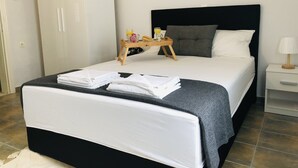 Een keurig opgemaakt bed met een zwart hoofdbord, een nachtkastje met een lamp en een dienblad met ontbijtartikelen.