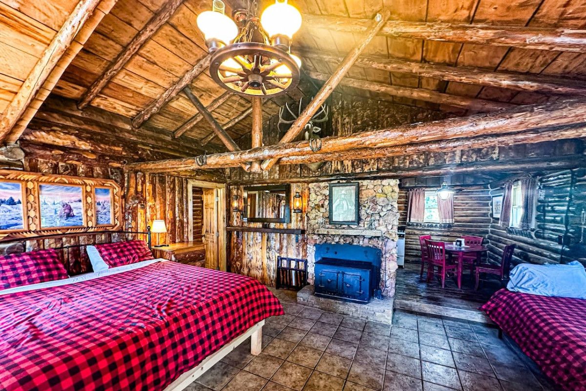 Ein rustikales Blockhaus-Interieur mit einem großen Bett, einem Kamin und einem Essbereich.