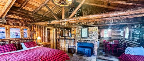 Ein rustikales Blockhaus-Interieur mit einem großen Bett, einem Kamin und einem Essbereich.