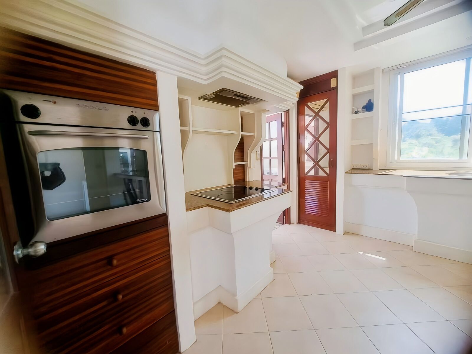 A modern kitchen with a built-in oven, a countertop, and a window.
