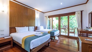 Une chambre d’hôtel avec deux lits, un plancher en bois, un balcon avec vue et un bureau avec une chaise.